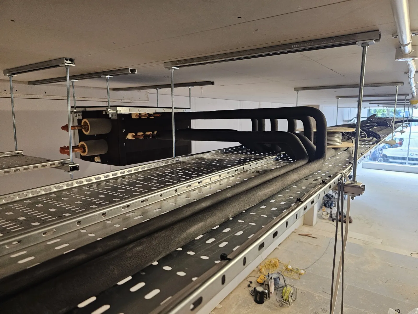 Insulated refrigerant pipework clipped to cable tray above a suspended ceiling
