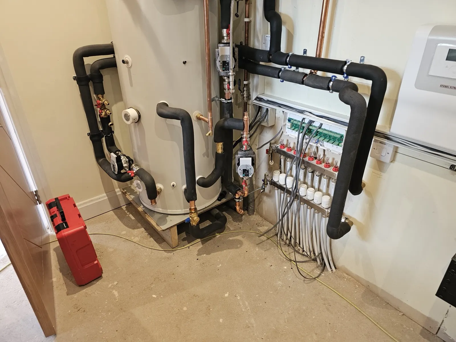 Underfloor heating manifold plumbed and wired beside the hot water cylinder